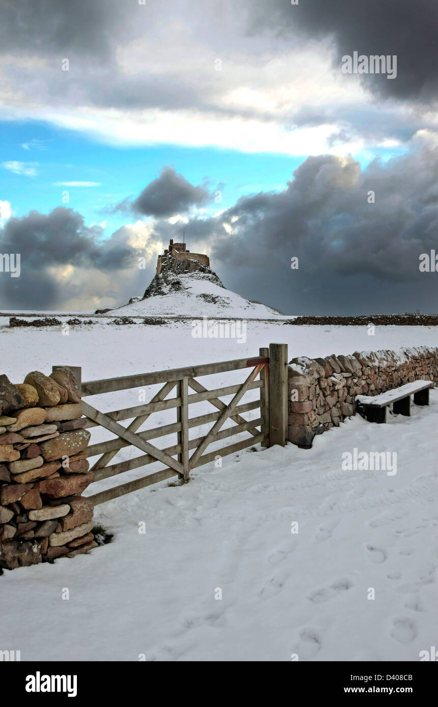 Lindisfarne Castle Holy Island, Northumberland sunset sky brooding clouds Snow dry Stone wall with wooden gate leads to castle Stock Photo