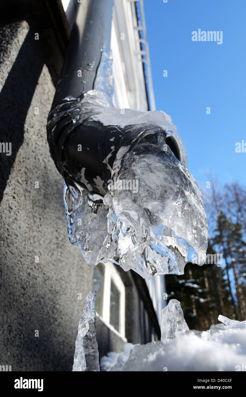 close-up of frozen drainpipe, wall and blue sky Stock Photo