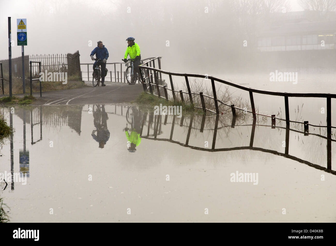 Cyclists survey a flooded cycle path next to the New Cut of the River Avon in Bristol after a particularly high spring tide. Stock Photo