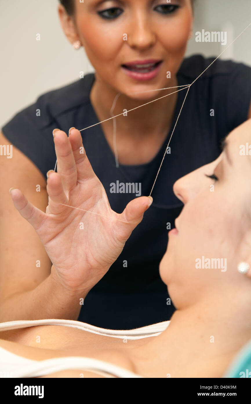 Beautician threading a clients eyebrows. Stock Photo