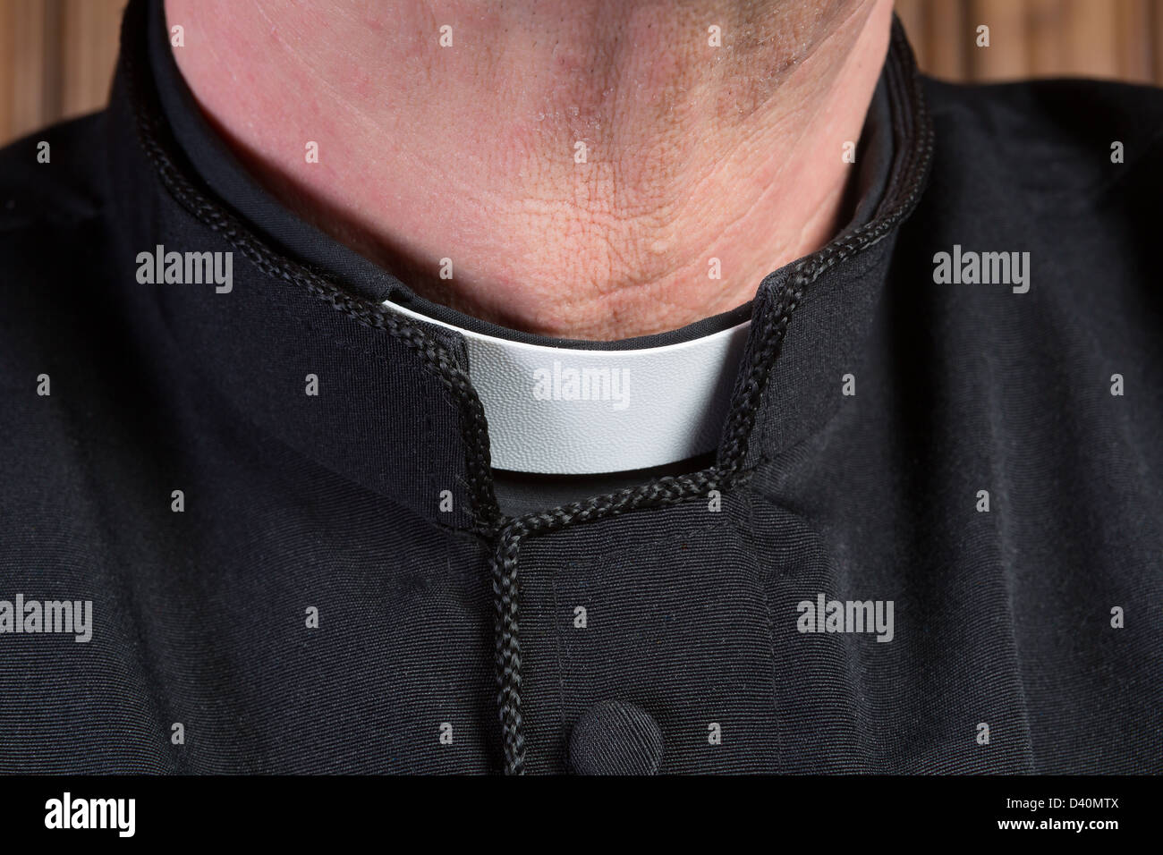 Closeup of the neck of a priest wearing a black shirt with cassock and white clerical collar Stock Photo