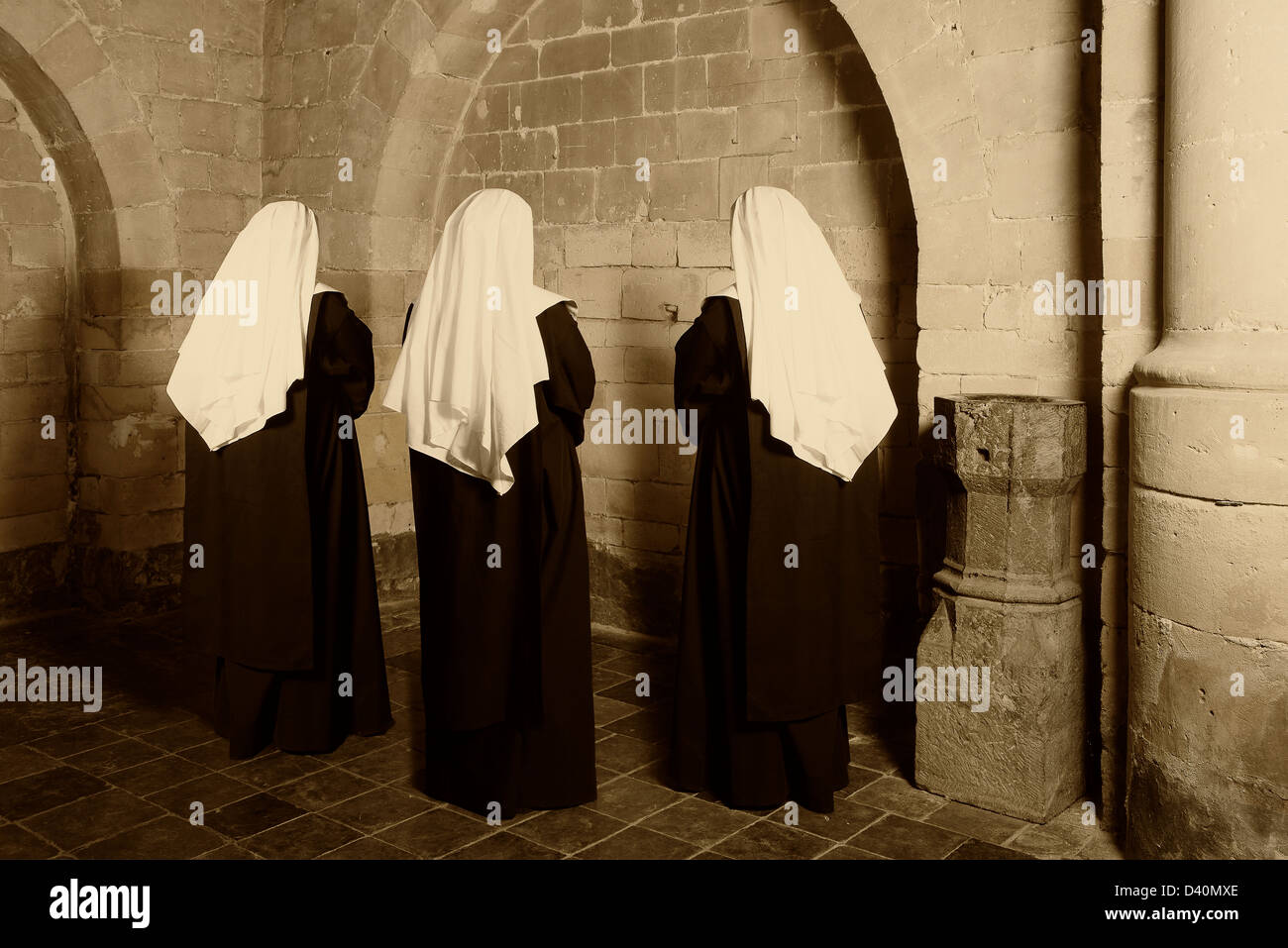 Three nuns in habit standing in a medieval abbey Stock Photo
