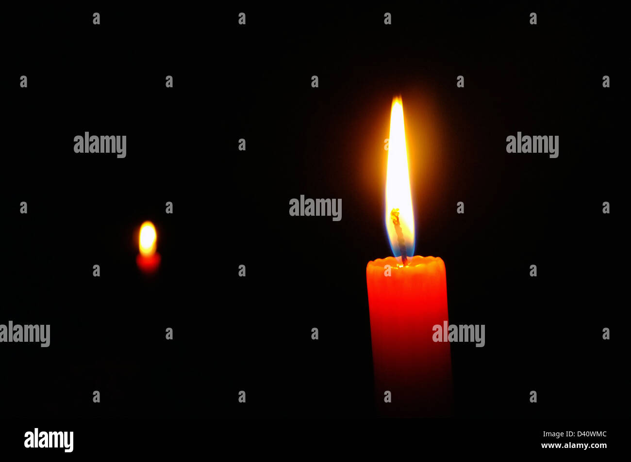 Two red candles burning brightly in darkness Stock Photo Alamy