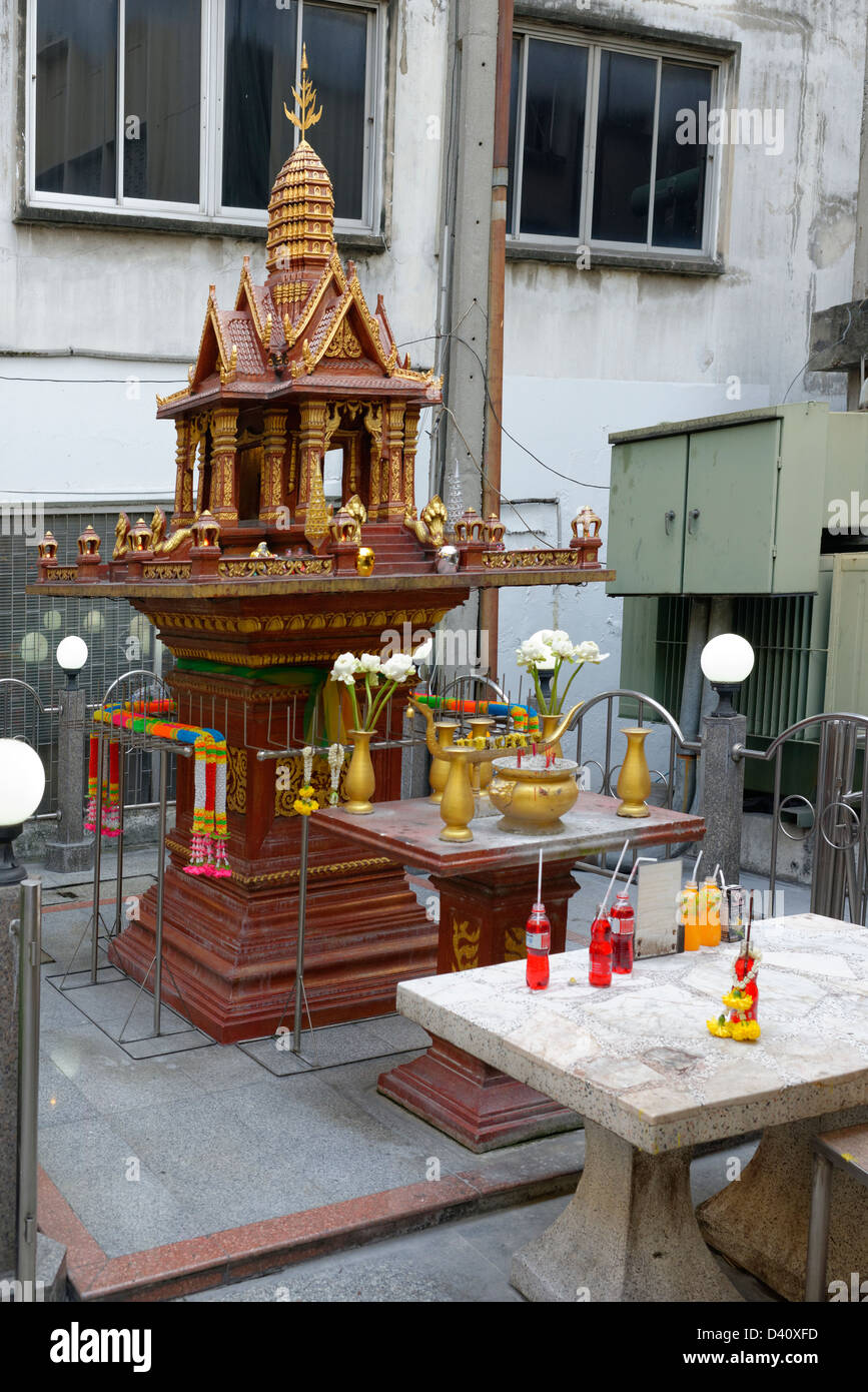 Buddhist street shrine in Bangkok with flowers Stock Photo
