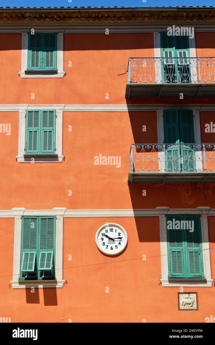 Clock on the front of brightly painted houses in Sospel, Provence, France Stock Photo
