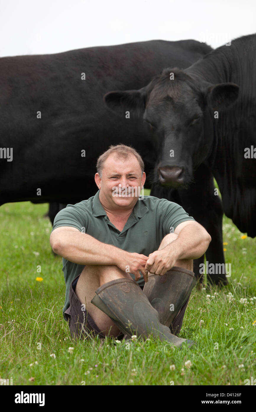 Beef Farmer sitting in field with livestock Stock Photo Alamy