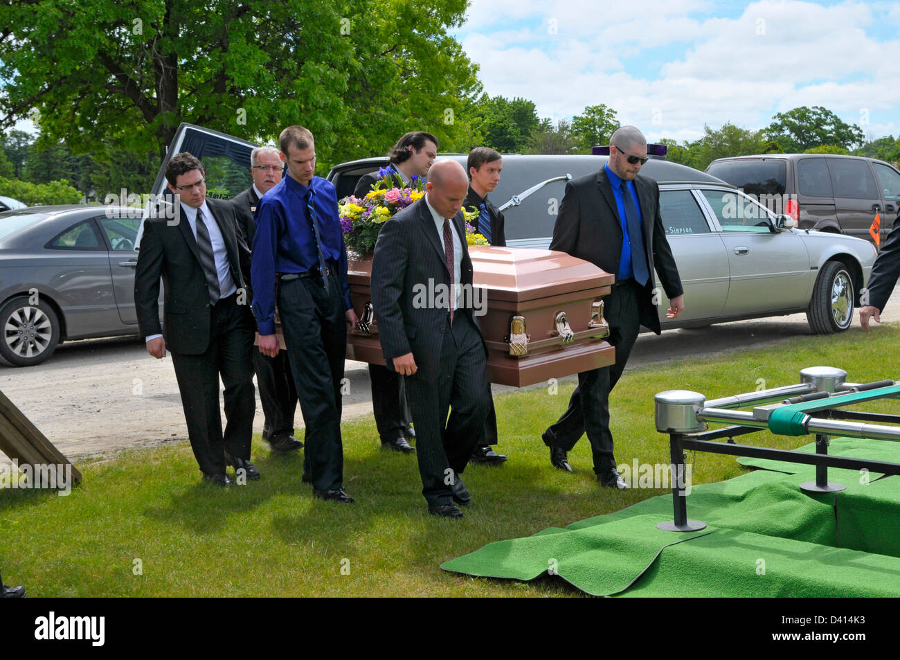 Funeral ending at cemetary gravesite with mourners and pallbearers Stock Photo