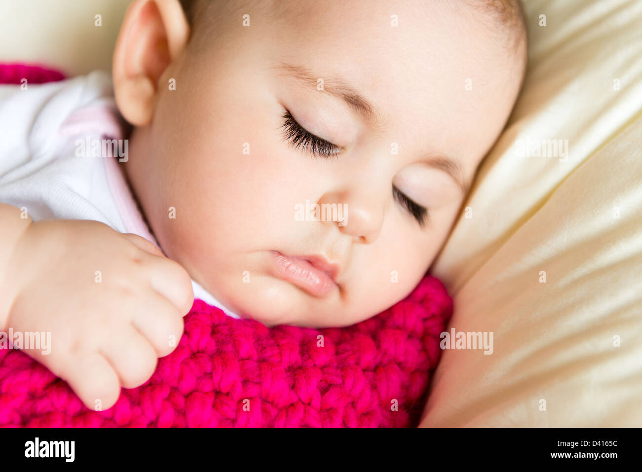 Closeup portrait of sleeping baby in pink knitted blanket Stock Photo