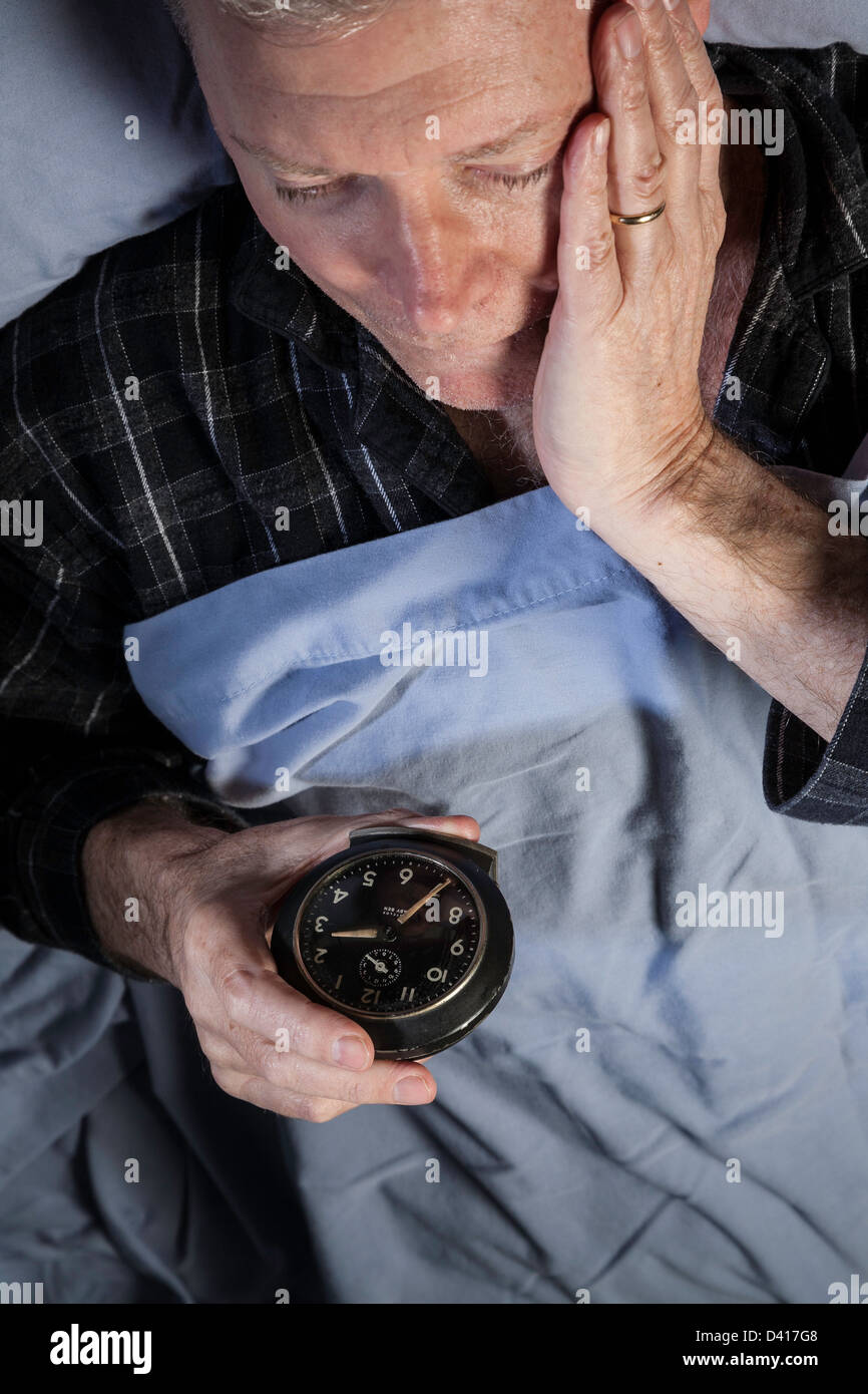 Mature man Sleepless, Tossing and Turning, Looking at Clock Stock Photo