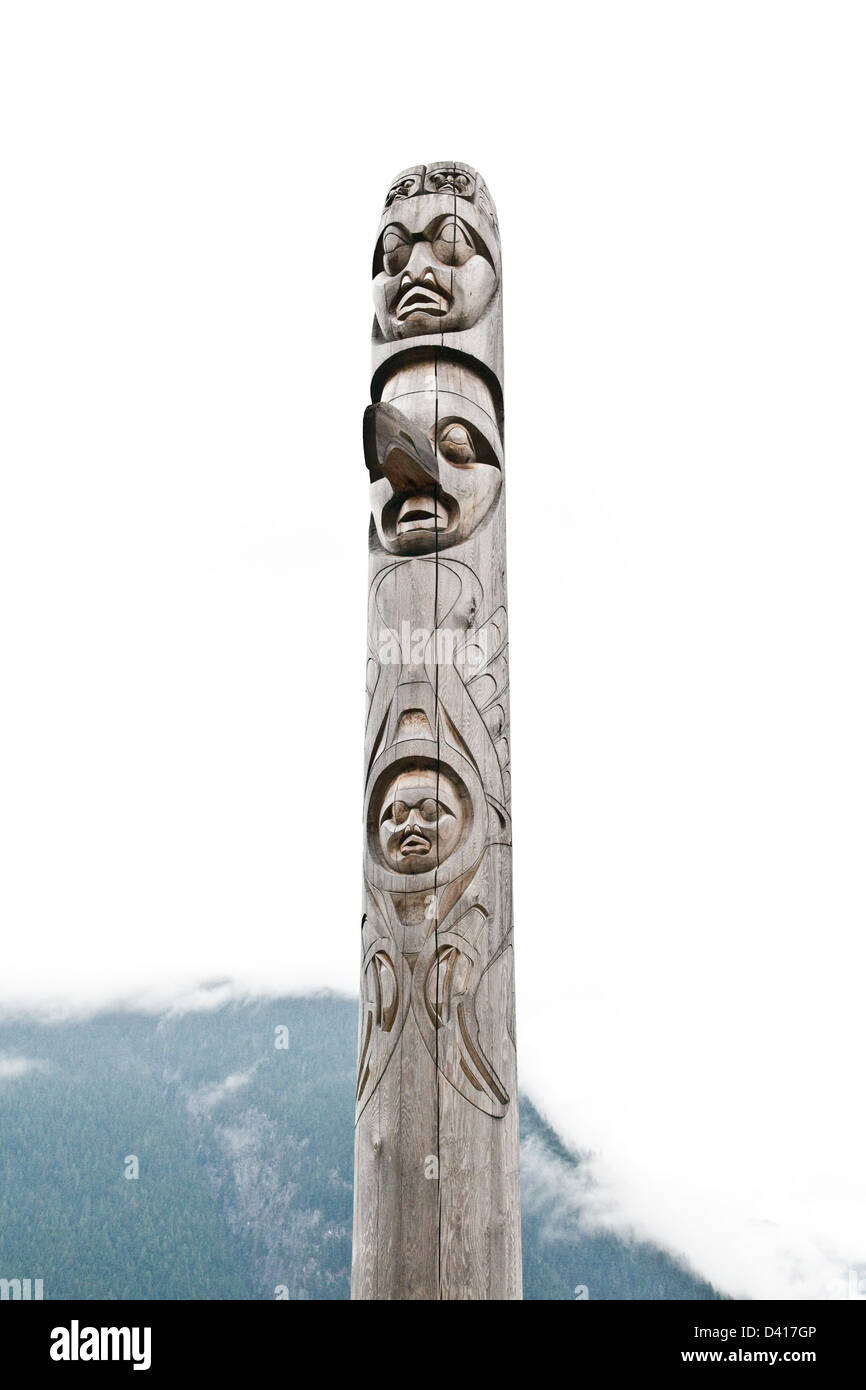 A totem pole carved in the Nuxalk tradition in the Great Bear Rainforest in the town of Bella Coola, British Columbia, Canada. Stock Photo