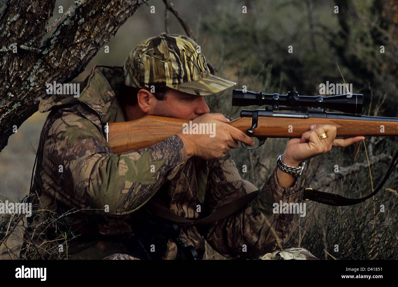 A South Texas deer hunter looking through his scope and aiming a rifle Stock Photo