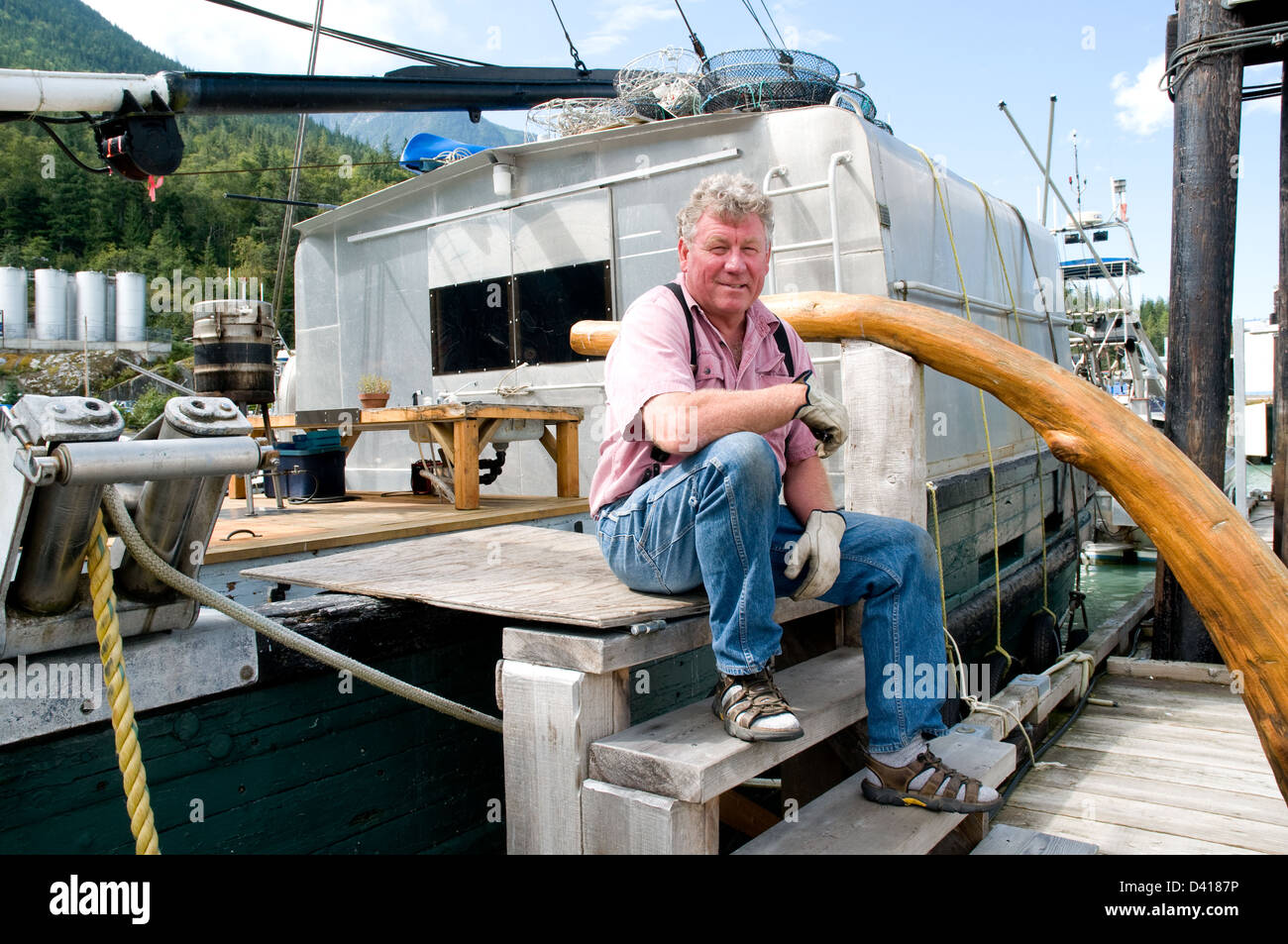 A resident of Bella Coola, sitting on his boat in the town's marina, in the Great Bear Rainforest, British Columbia, Canada. Stock Photo