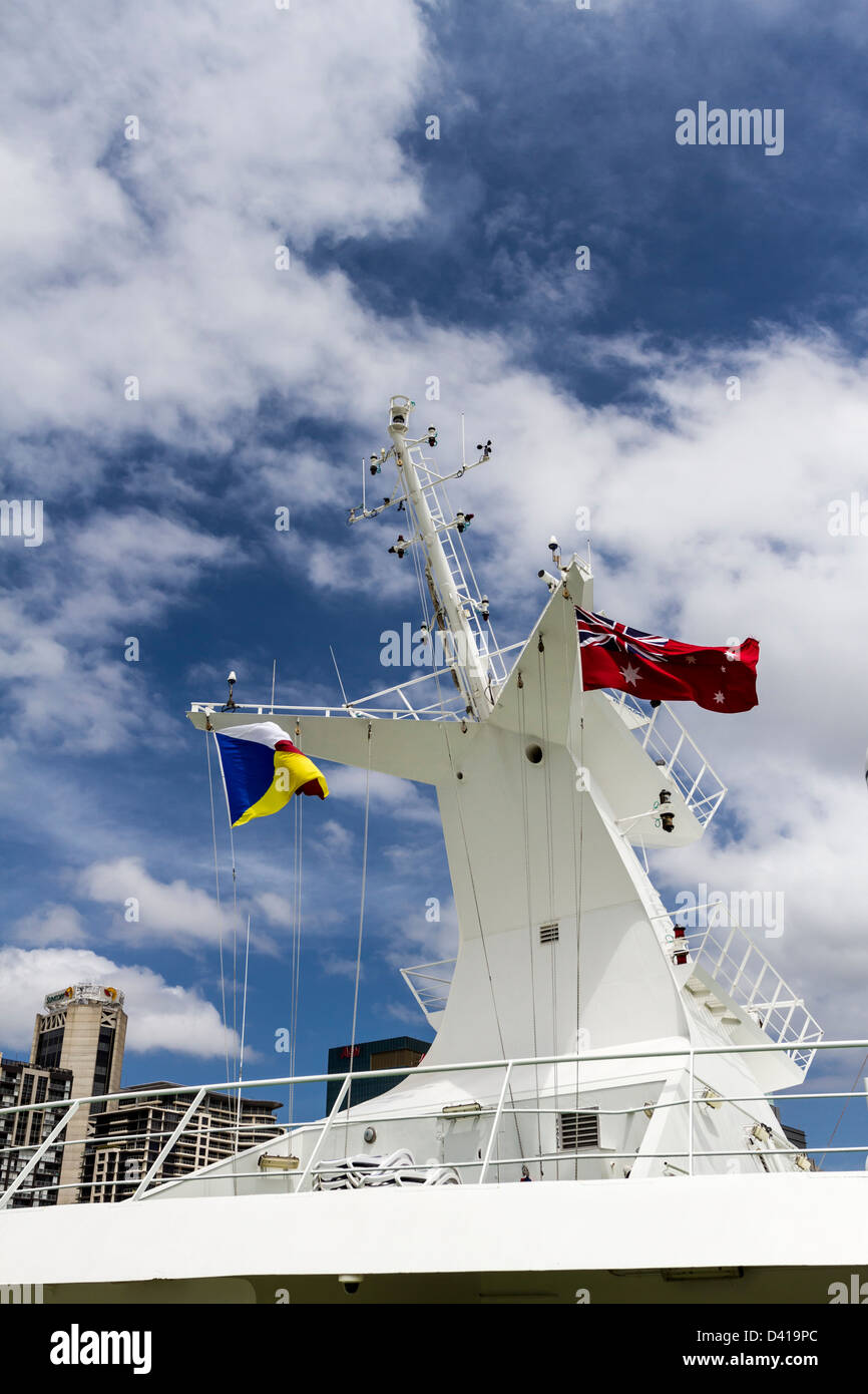 Cruise ship communications and flag masthead, city skyline in background. Stock Photo