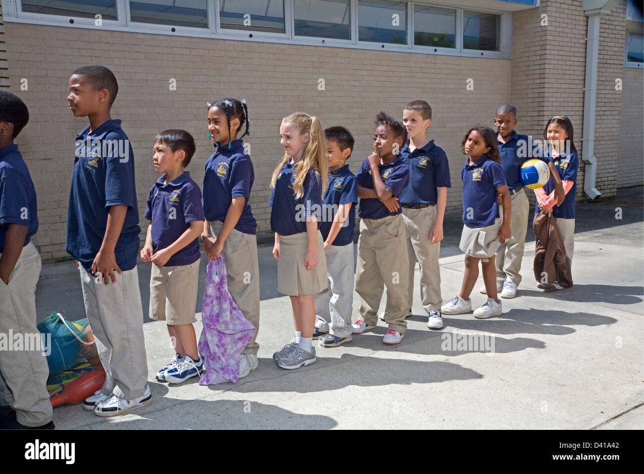 Grade school mixed race children in uniforms wait in line outdoors at school in Louisiana Stock Photo