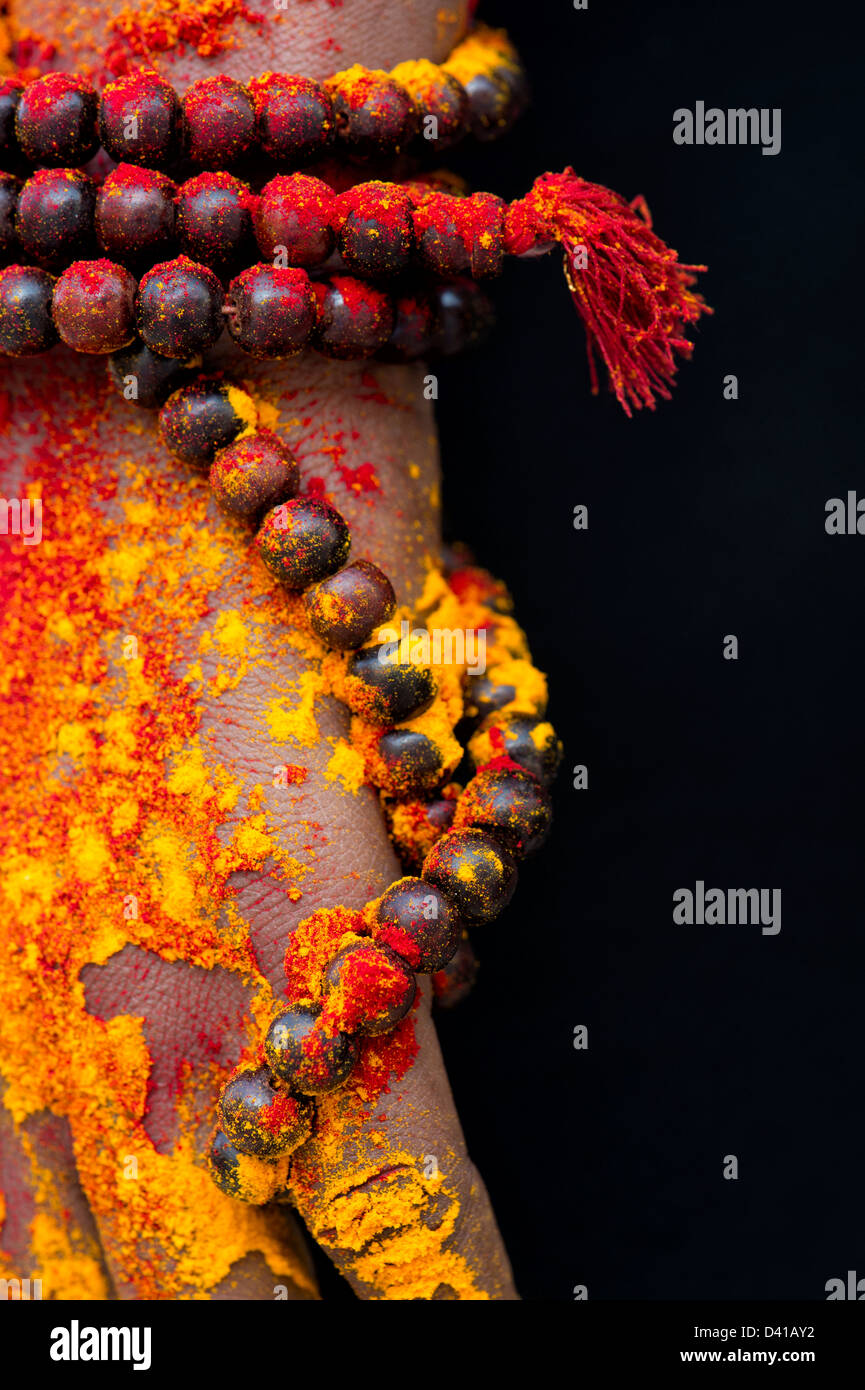 Japa Mala prayer beads around an Indian mans hand covered with coloured powder. India Stock Photo