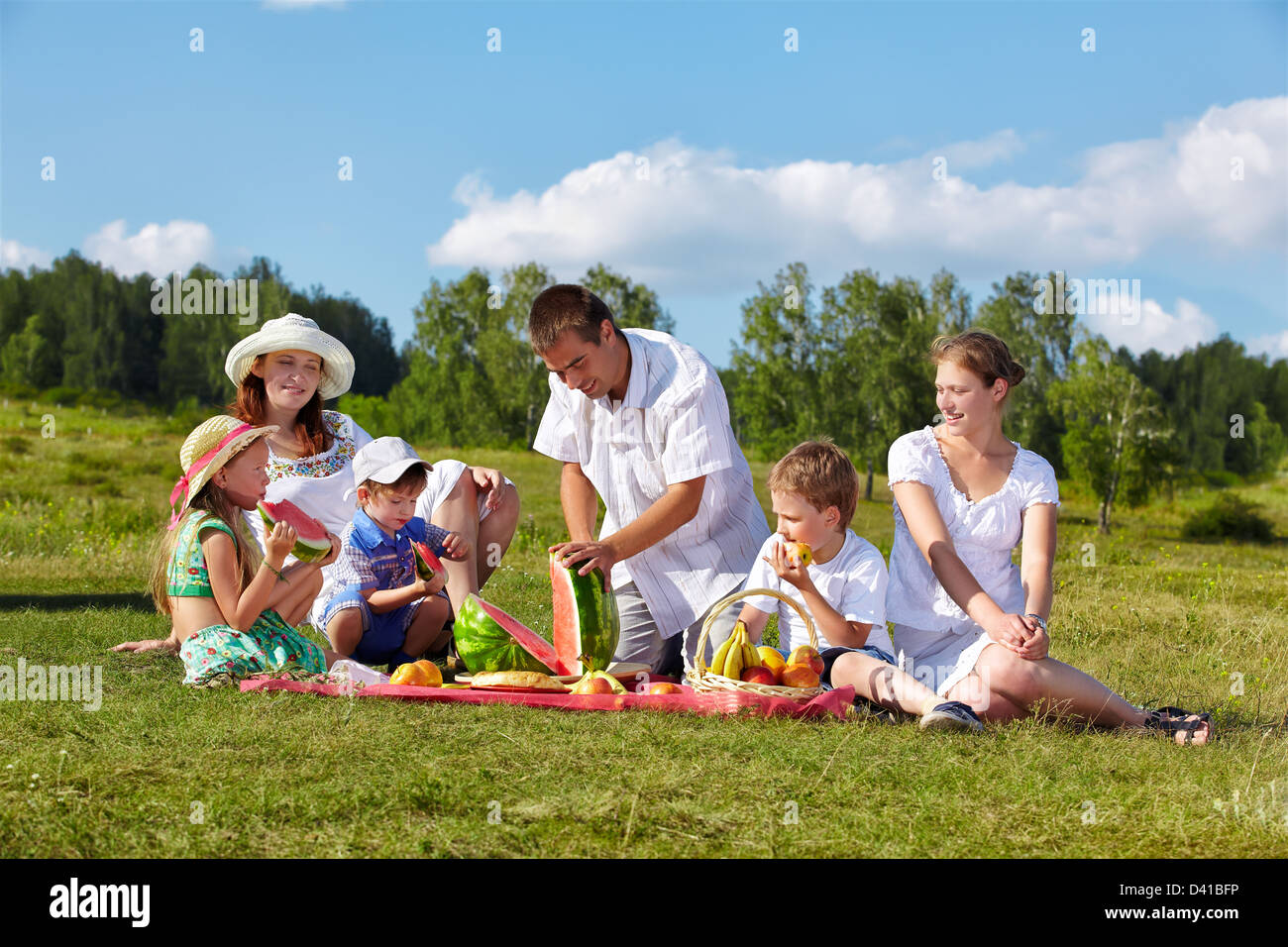 outdoor group portrait of happy family having picnic on green grass in