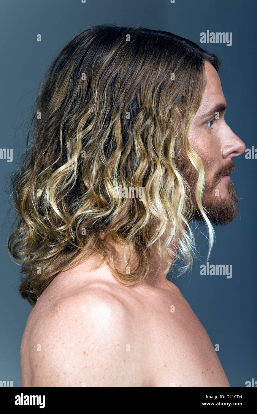 a portrait side profile of a Caucasian male with shoulder length styled hair with blond steaks or highlights. he is bare skinned Stock Photo
