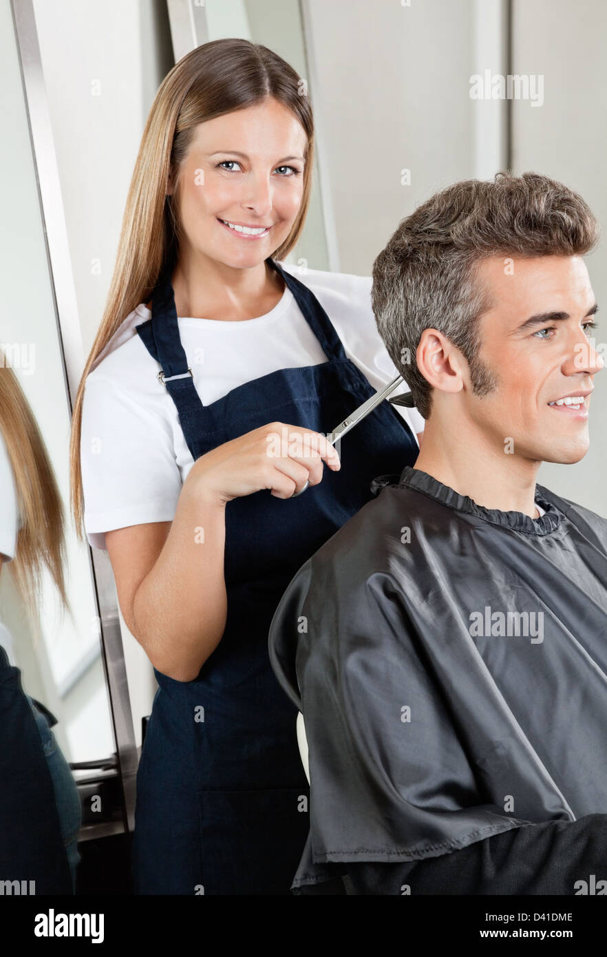Hairdresser Cutting Client's Hair In Salon Stock Photo