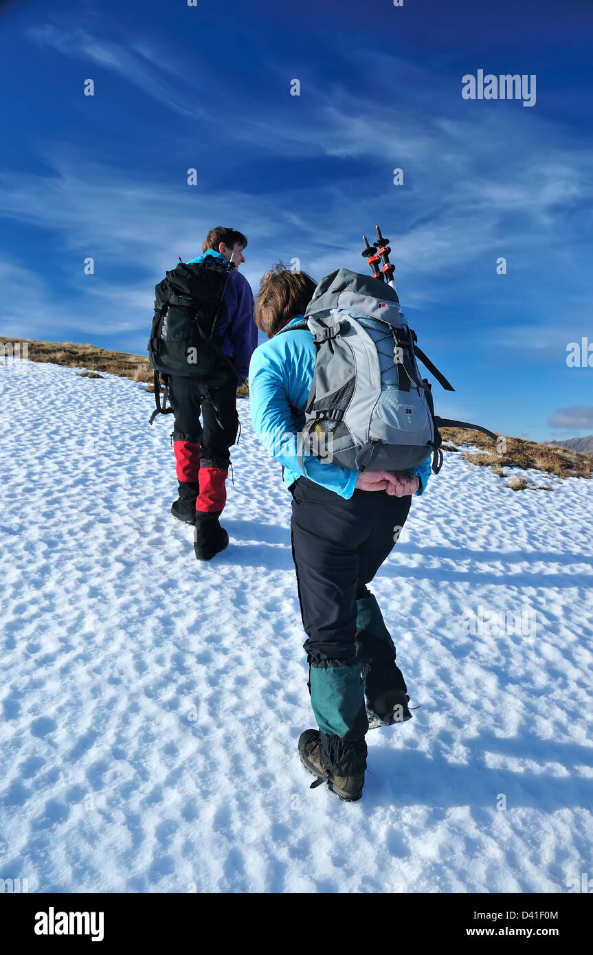 Two hillwalkers climb up hard snow on the Corbett Beinn Mhic Mhonaidh Stock Photo