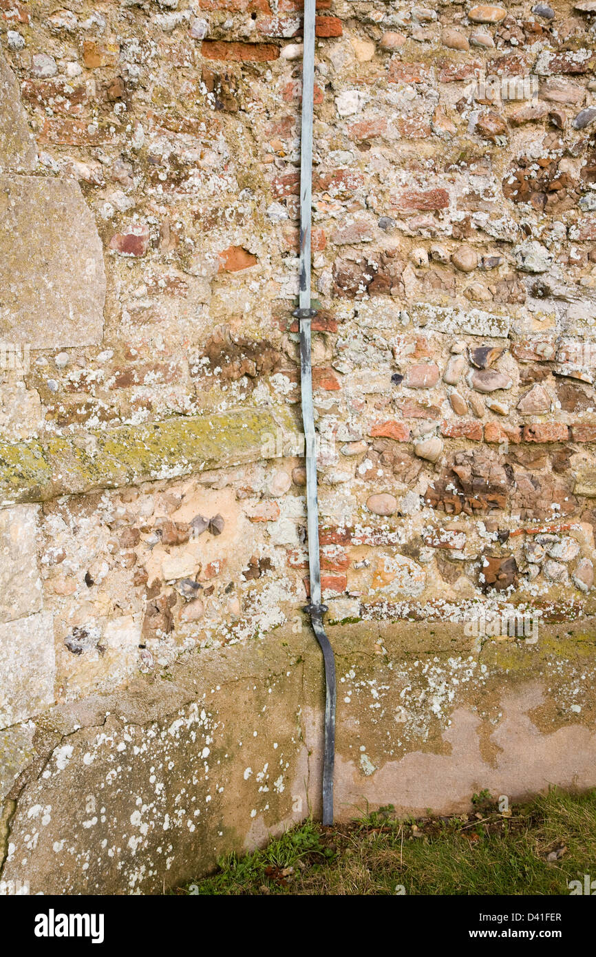Copper lightning conductor running down a church wall into the ground
