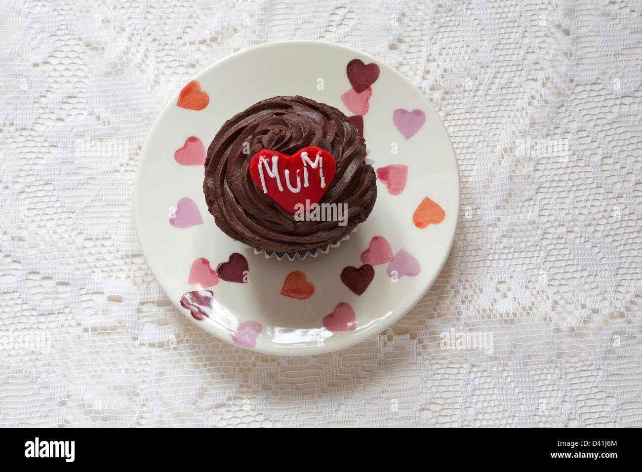 chocolate cupcake with the word mum iced on red heart for Mothering Sunday, Mothers Day set on plate with hearts on Stock Photo