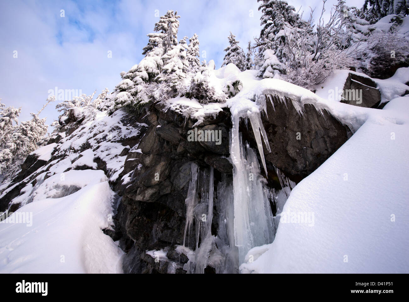 Icicles hanging from rocks on the side of a mountain in winter Stock Photo