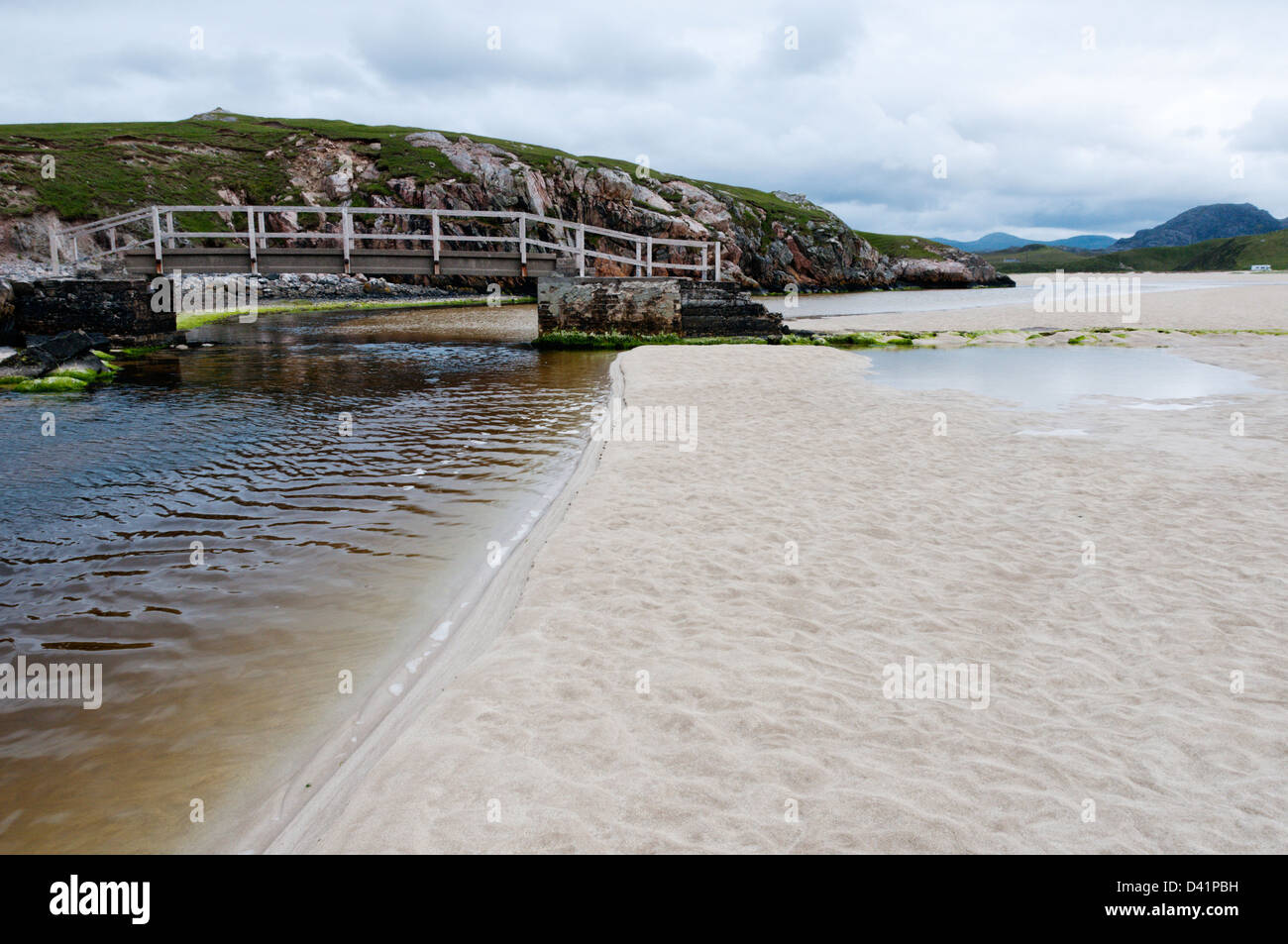 A footbridge across a small stream onto the sands at low tide at Tràigh Ùige on the Isle of Lewis in the Outer Hebrides. Stock Photo