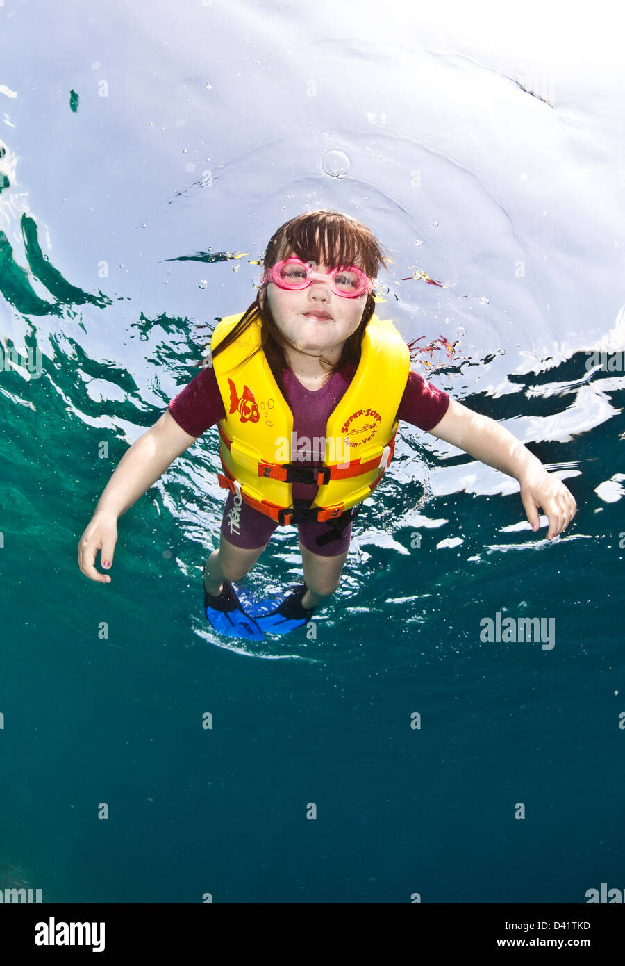 Girl in yellow life jacket holding her breath, underwater view
