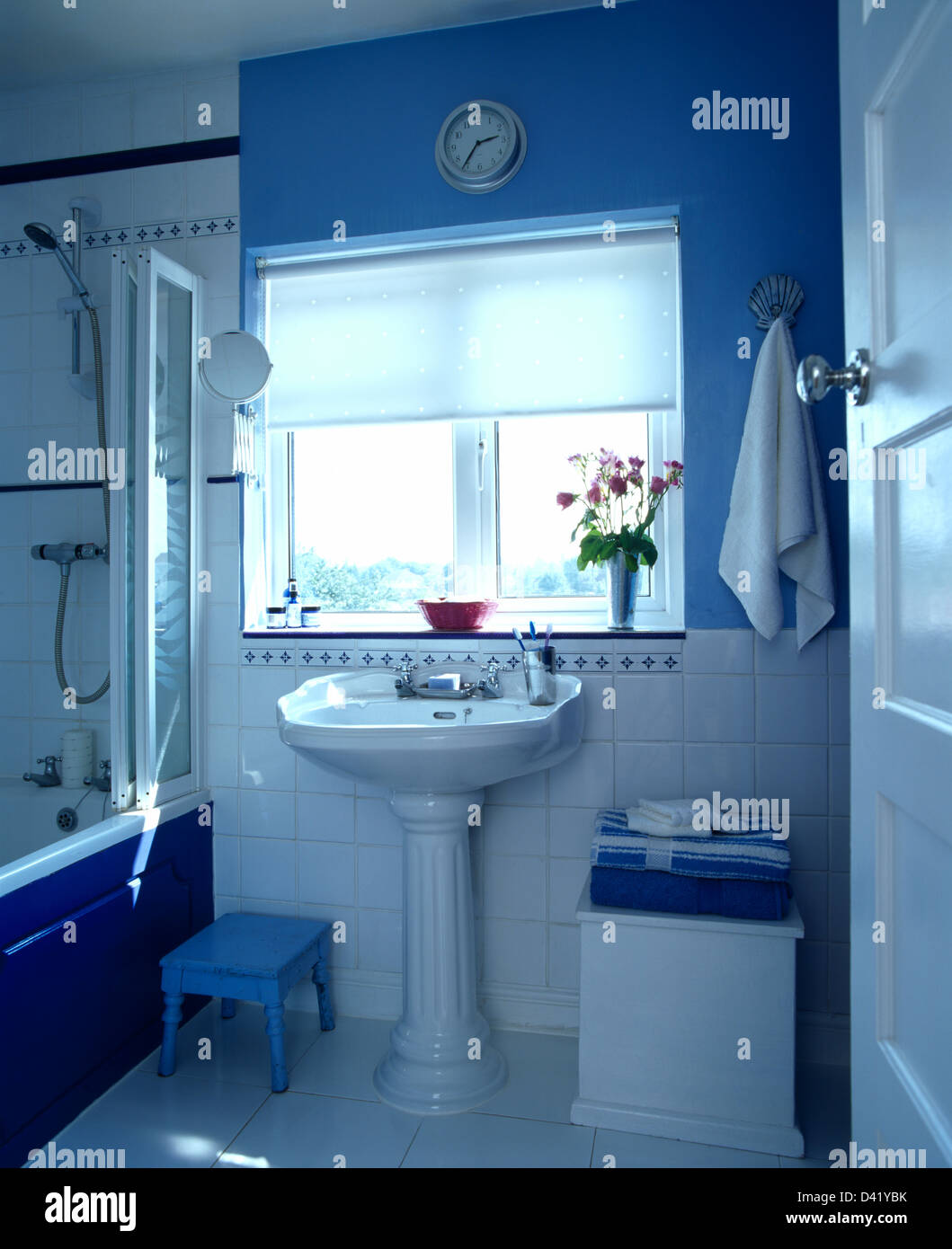 White blind on window above pedestal basin in blue and white bathroom