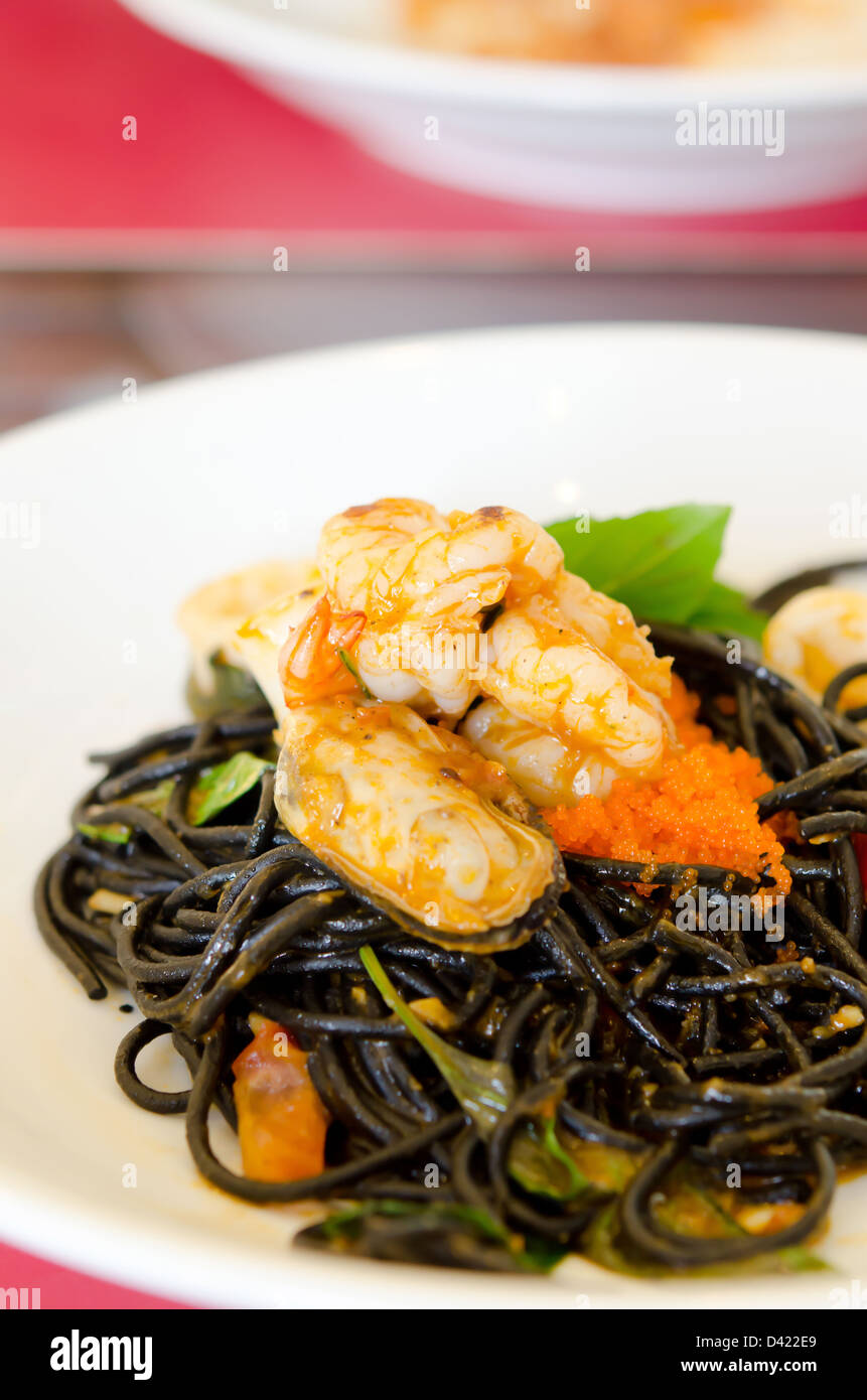 Black spaghetti with green mussel , fish eggs and shrimp on white plate