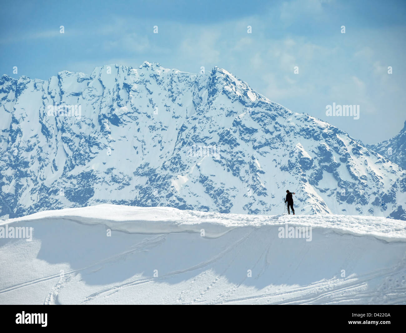 Lonely skier climbing mountain summit in winter Stock Photo