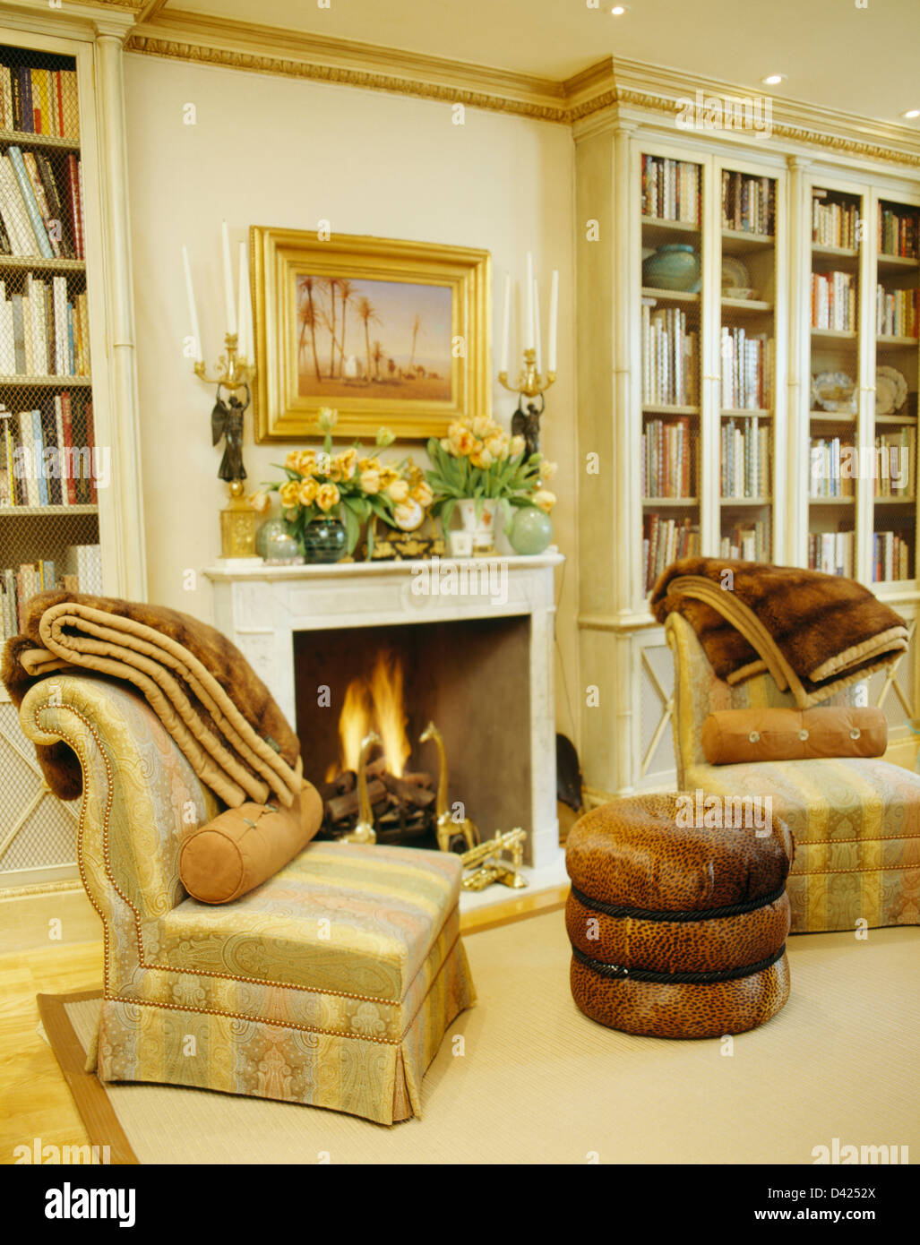 Faux fur throws on chairs beside fireplace with lighted fire in