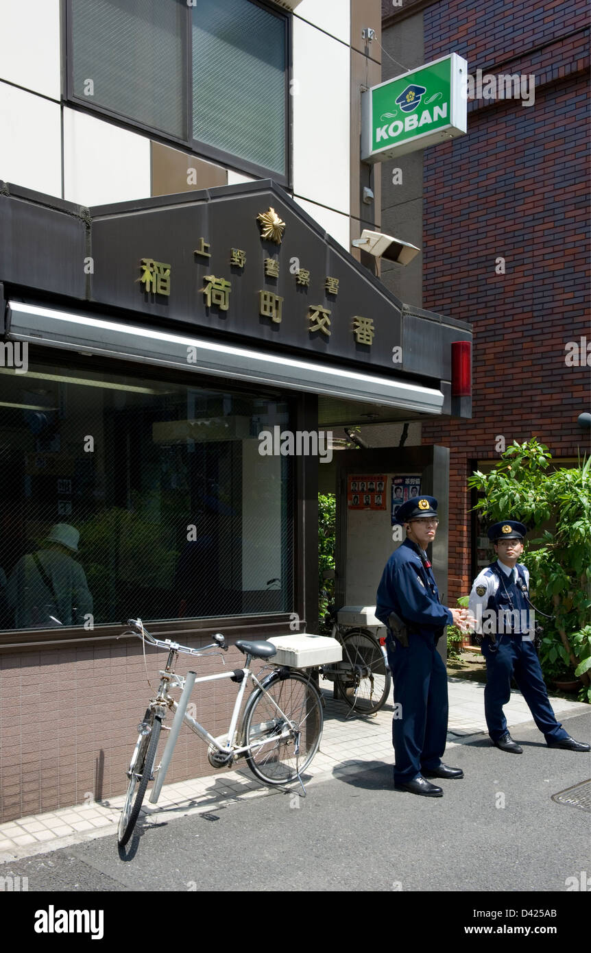 Two police officers standing outside a neighborhood koban, or police box, in downtown Ueno, Tokyo, Japan. Stock Photo