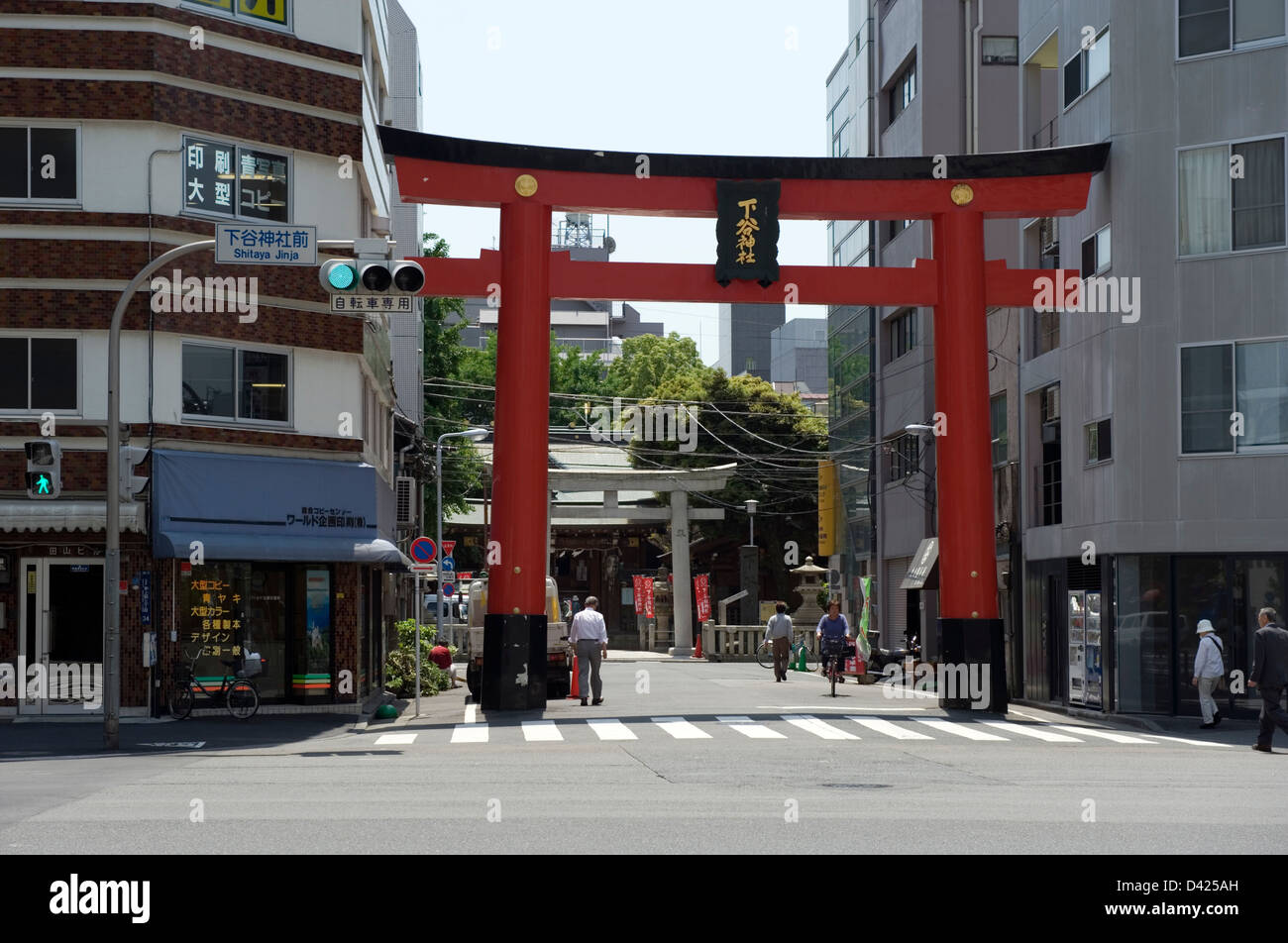 Large torii shrine gate squeezed between buildings marks the entrance to the neighborhood shrine Shitaya Jinja in Ueno, Tokyo Stock Photo