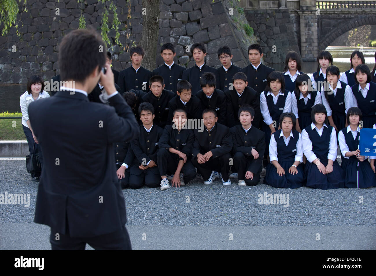 Group of high school students in uniform posing for commemorative photo at Tokyo's famous Imperial Palace Nijubashi Bridge Stock Photo