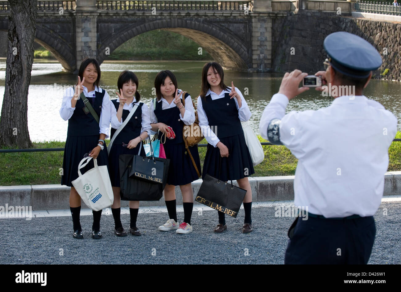 Security guard taking commemorative photo of high school girls at Tokyo's famous Imperial Palace Nijubashi Bridge. Stock Photo