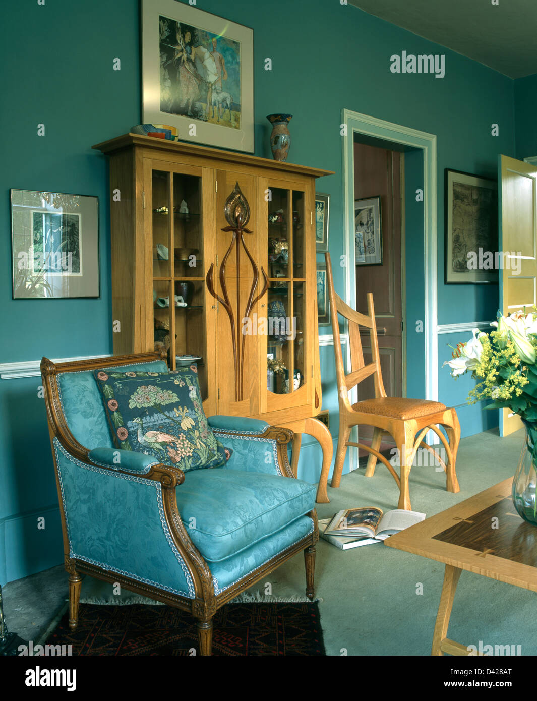 Turquoise blue damask armchair and pale wood glassfronted in