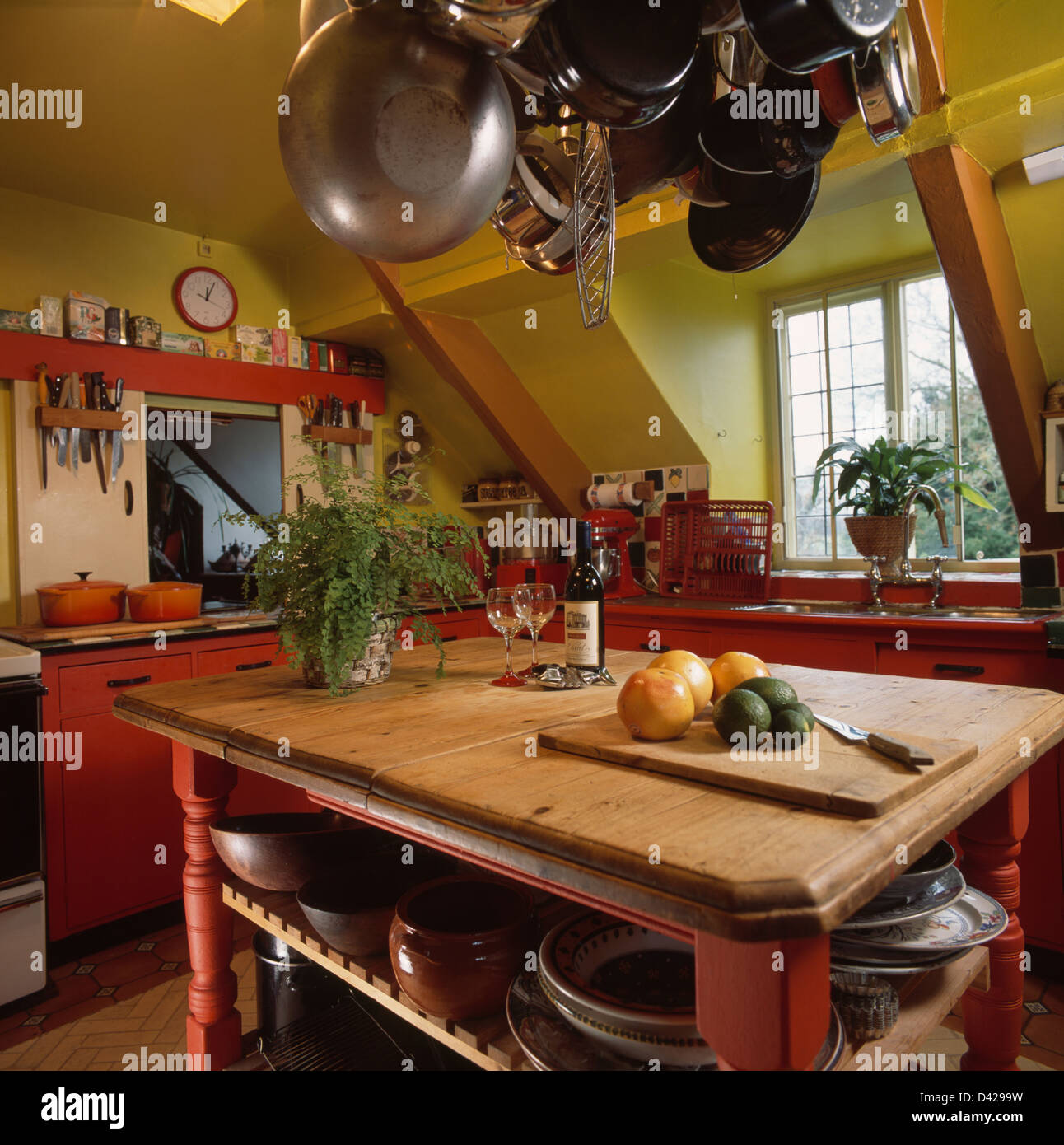 Pans hanging on rack above wooden island unit in red and green attic