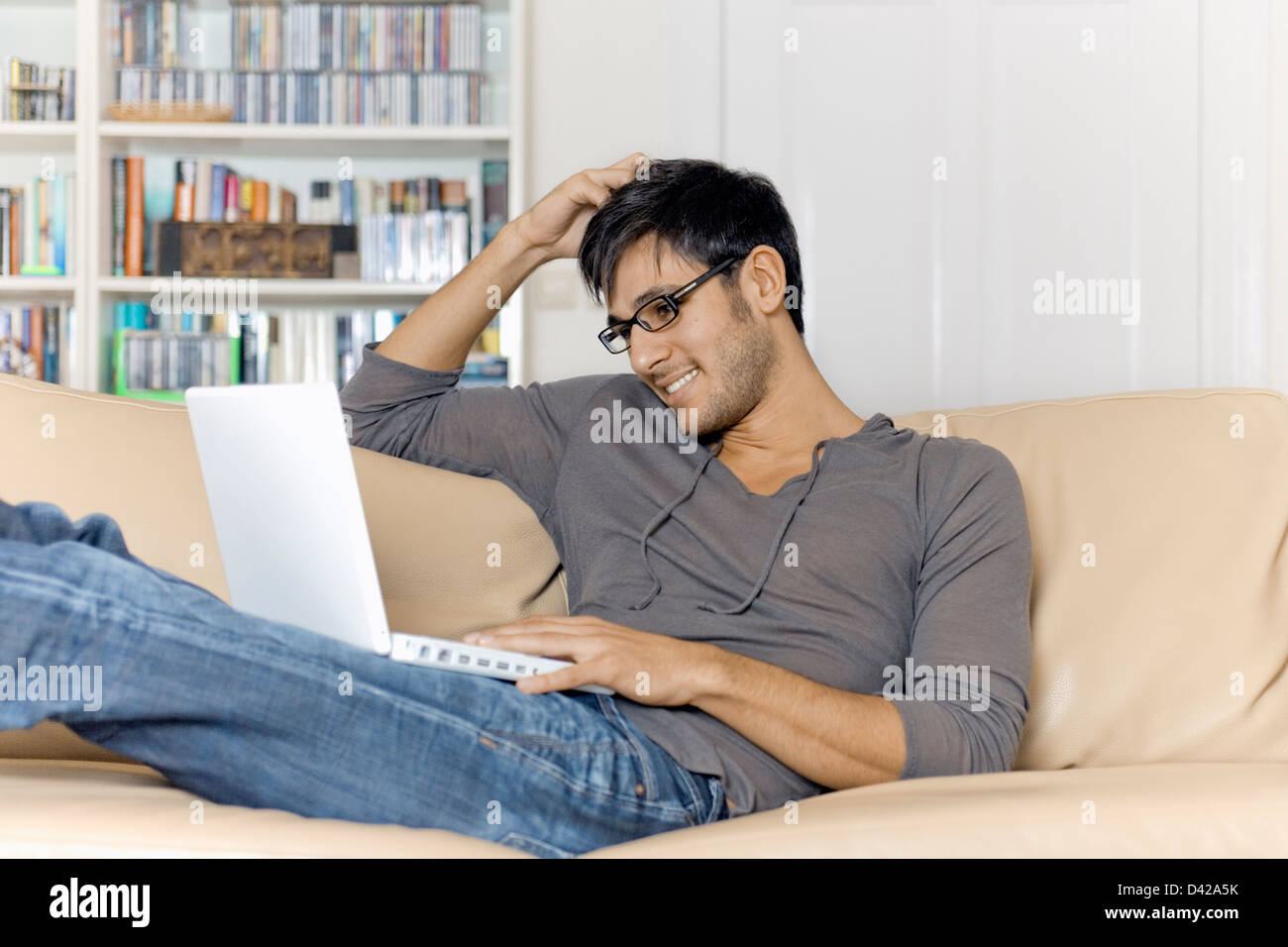 A man very comfortable surfing the internet using a laptop. Stock Photo