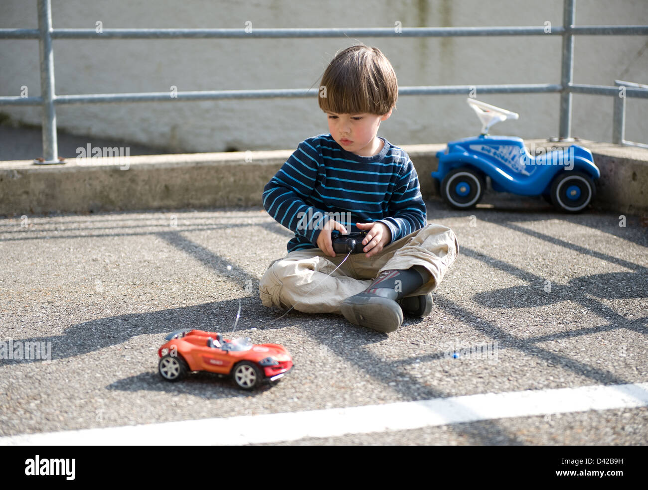 Carabietta, Switzerland, boy playing in a parking lot with his remote controlled car Stock Photo