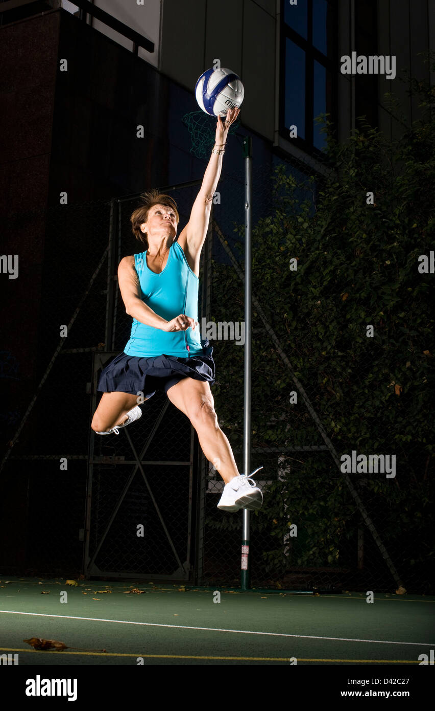 Netball player jumping to reach the ball Stock Photo