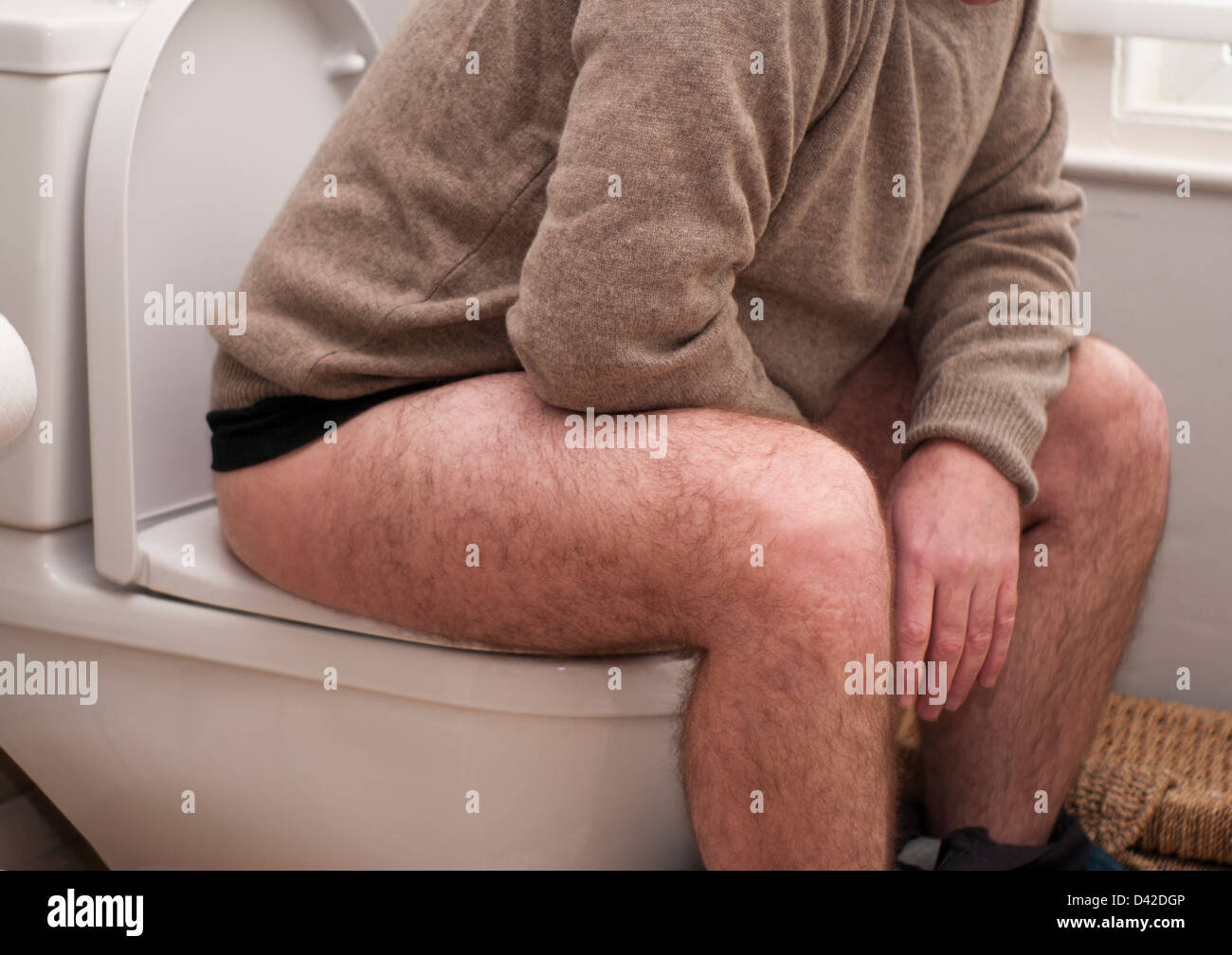 Man Sitting On The Toilet With His Trousers Down Stock Photo
