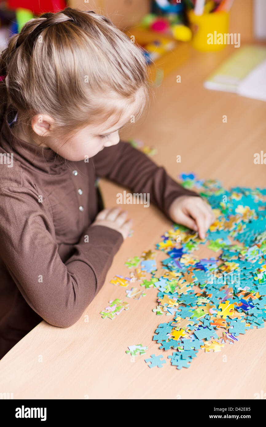 Cute little girl playing puzzles at the table Stock Photo Alamy