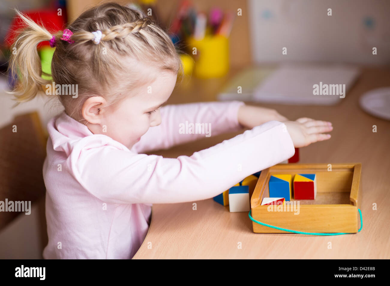 Cute little girl playing with blocks at the table Stock Photo - Alamy