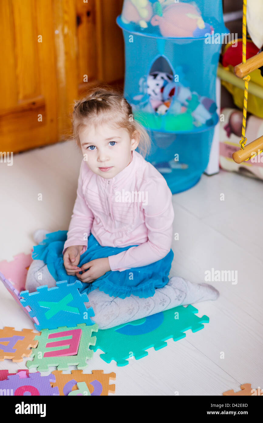 Cute little girl playing puzzles on the floor Stock Photo - Alamy