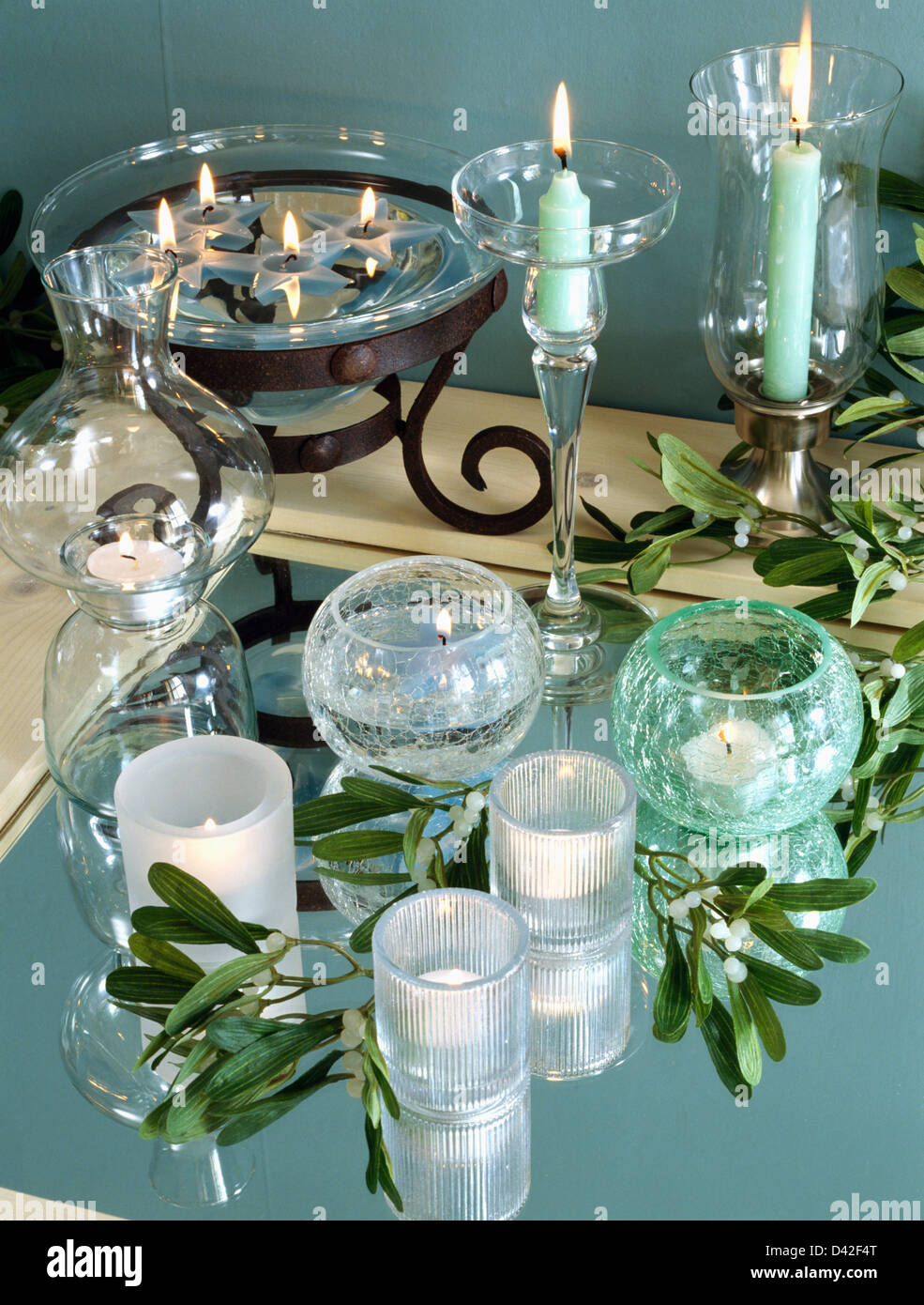 Close-up of glass candle holders and bowl with lighted turquoise and white candles Stock Photo