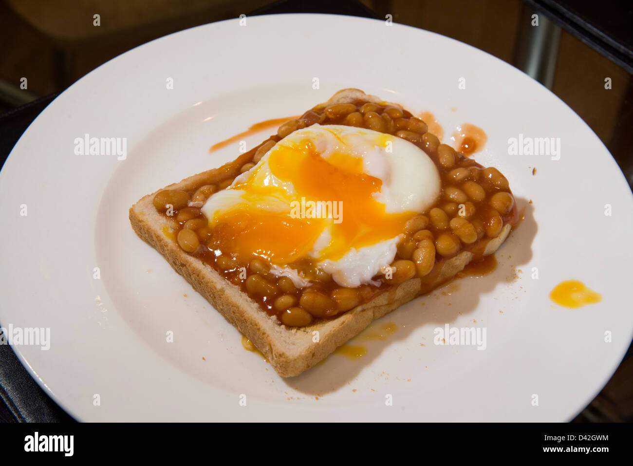 A plate of baked beans on toast with a poached egg on top Stock ...