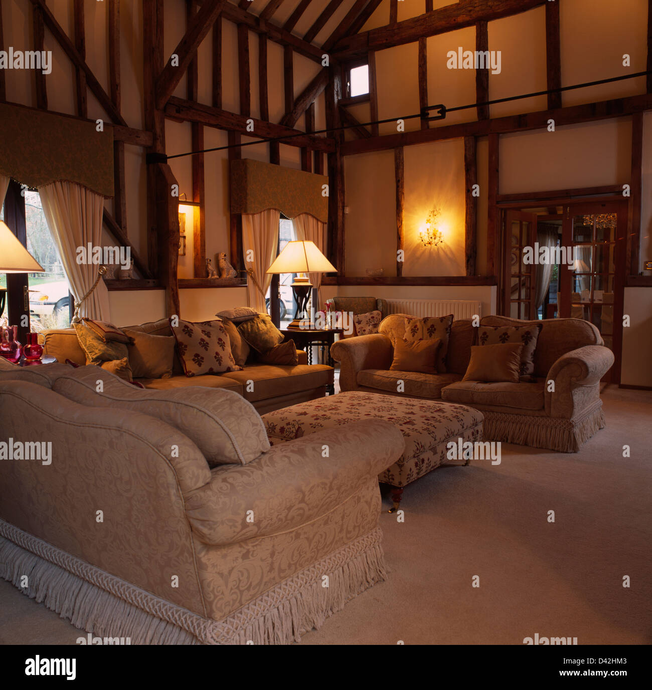 Comfortable sofas and lighted lamps in double height barn conversion