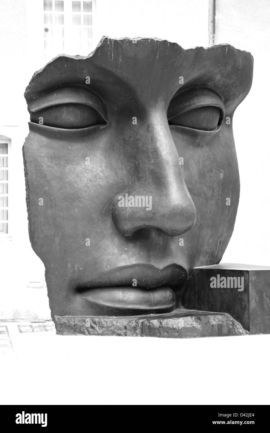 Selective focus on a bronze face sculpture on a faded background shot