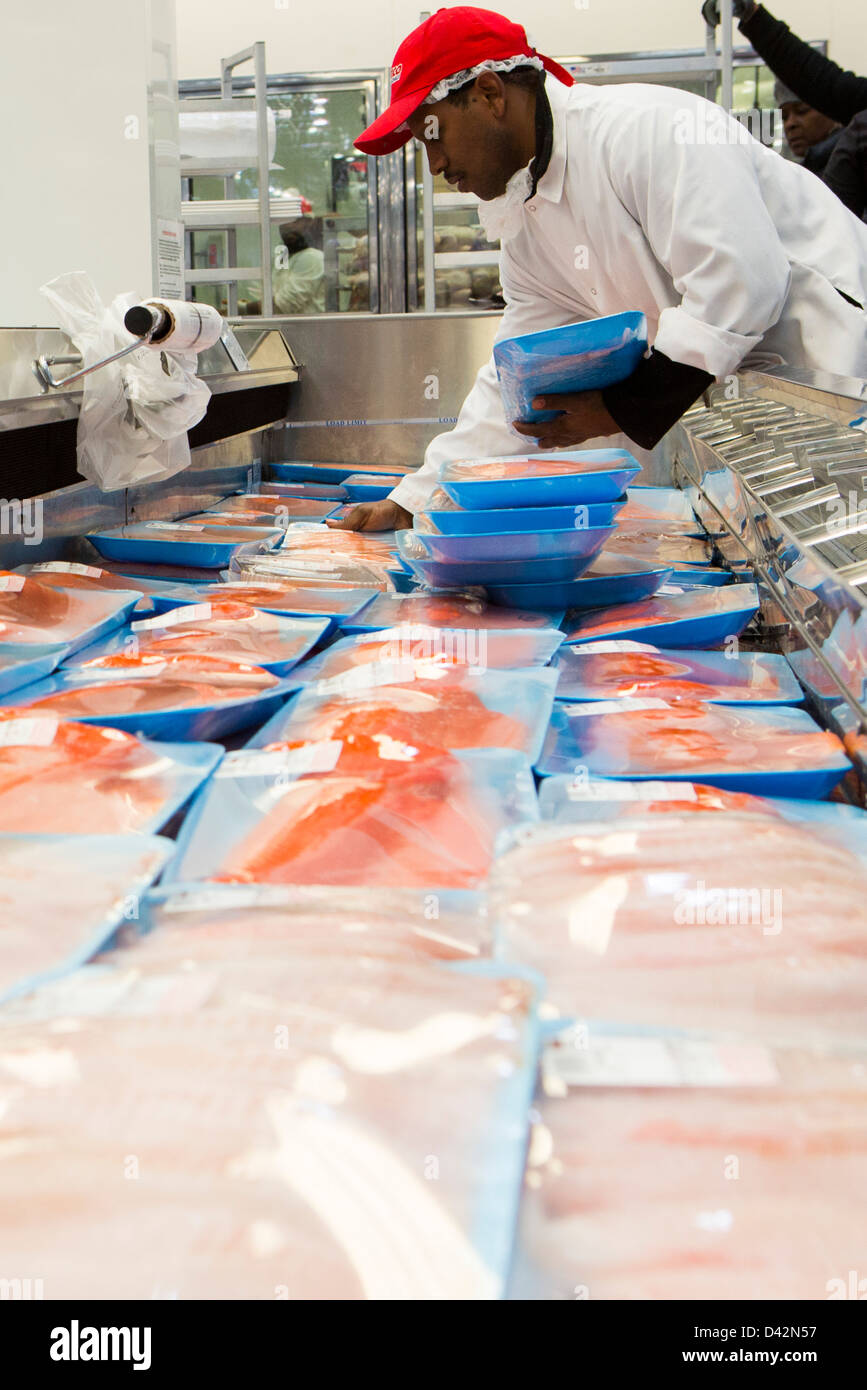 A Costco employee stocking salmon fillets at a Costco Wholesale